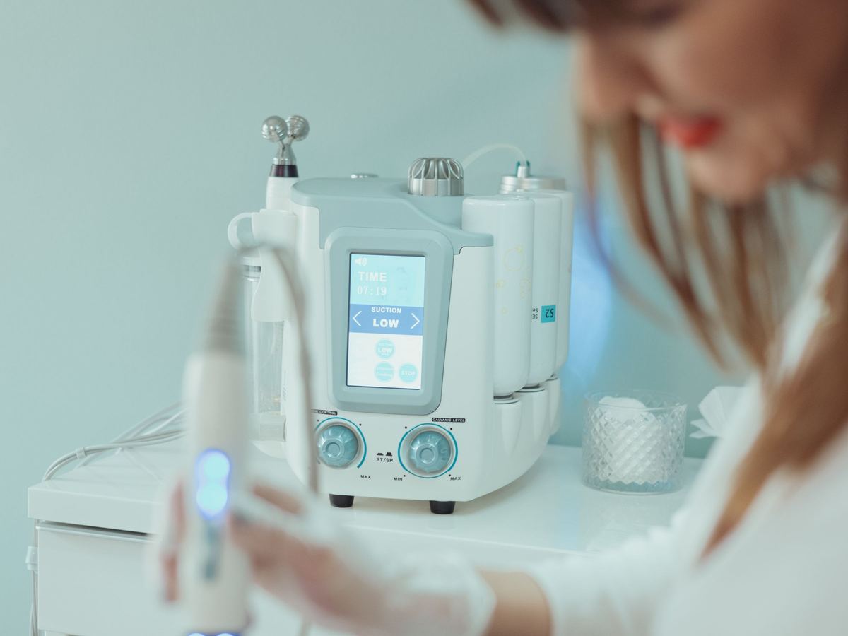 L'appareil Hydrafacial en cours d'utilisation sur le visage d'une cliente, en cabine